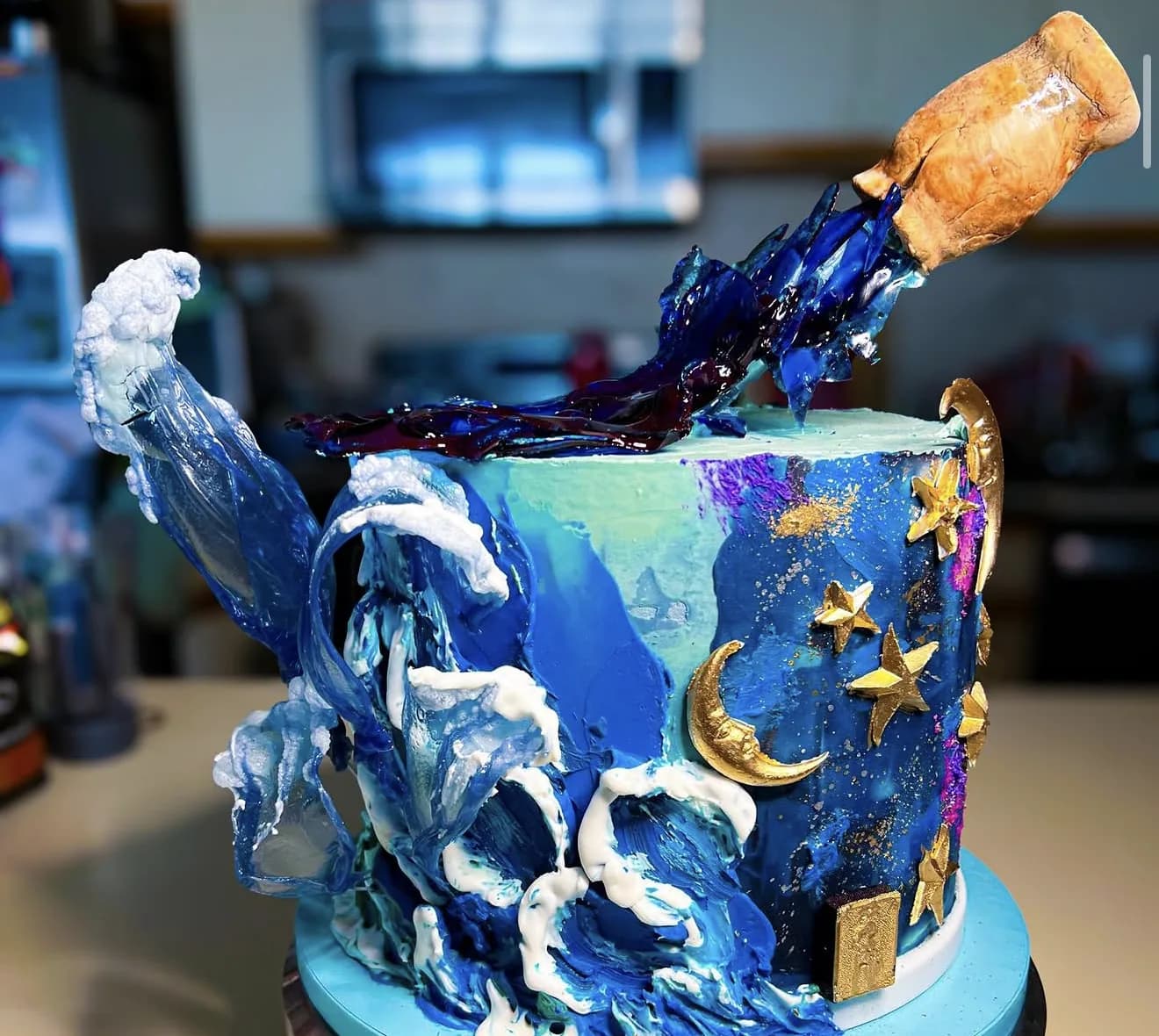 Ocean-themed cake with crashing waves, gold stars and moon, and a bottle pouring liquid effect
