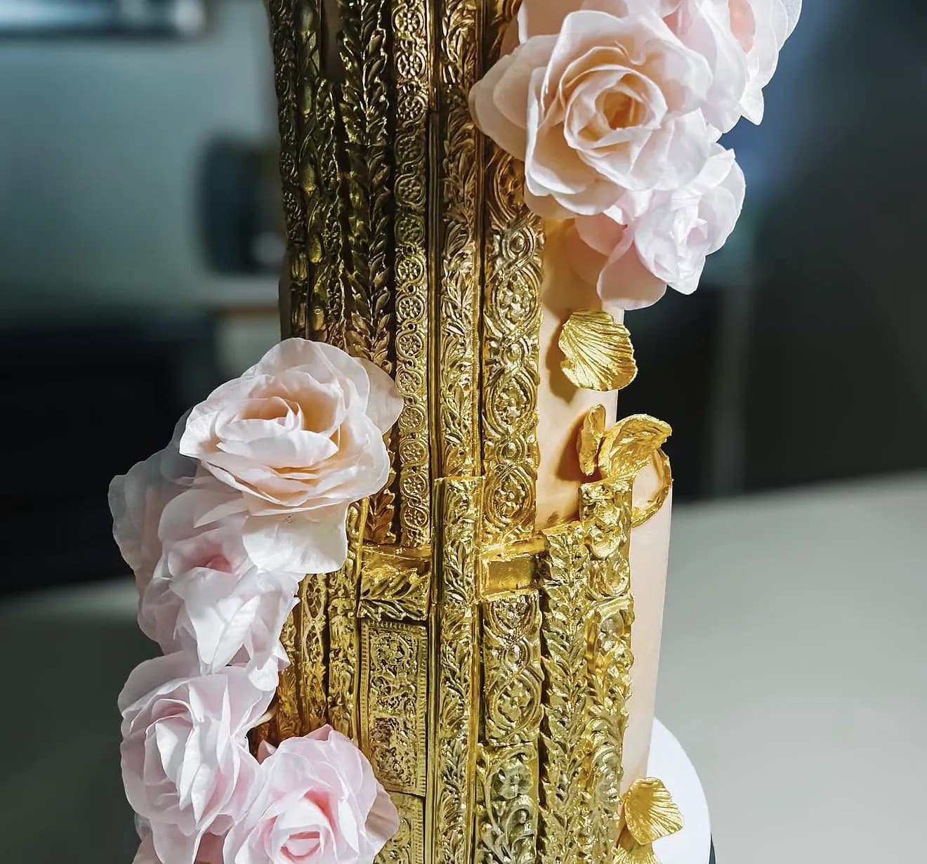 Detail of gold ornate panels and blush sugar roses on gilded baroque wedding cake